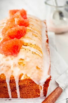 a loaf of bread with oranges on top and icing drizzled over it