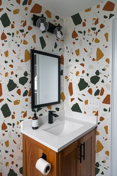 a bathroom vanity with a mirror, sink and toilet paper roll on the wall next to it