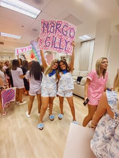 two girls holding up a sign that says marcoo billy in front of them while others look on