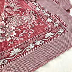 a red and white paisley print shirt laying on top of a bed