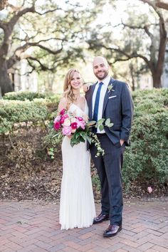 a bride and groom pose for a photo in front of some trees at their wedding