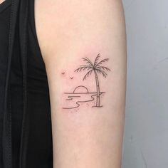 a woman's arm with a small palm tree on the beach