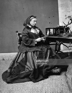 an old black and white photo of a woman sitting at a desk