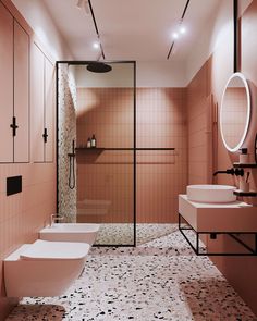 a bathroom with pink walls and flooring has two sinks, a toilet, and a shower stall