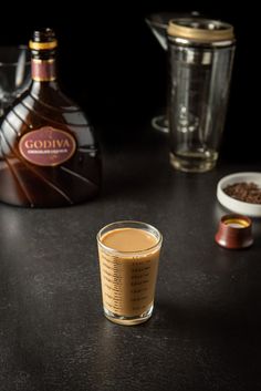 a shot glass sitting on top of a table next to a bottle of liquid and spices