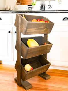 a wooden stand with two bins filled with fruit on top of a hard wood floor