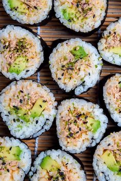 several sushi rolls with various toppings are arranged on a bamboo mat, ready to be eaten