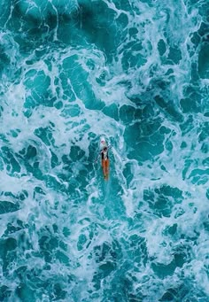 an aerial view of a person swimming in the ocean with foamy water around them