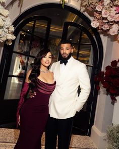 a man in a tuxedo and a woman in a gown pose for the camera