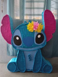 a blue stuffed animal with a flower in it's hair