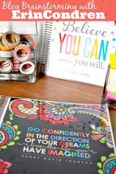 a table topped with lots of crafting supplies on top of a wooden table next to a notebook