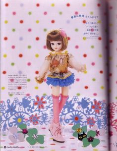 a doll is standing in front of a colorful background with flowers and polka dotes