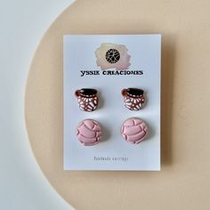 two pairs of pink and brown earrings on top of a white card with the words yyssik crazciones