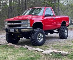 a red pick up truck parked in the woods