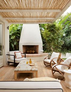 a living room with white furniture and a fire place in the center, surrounded by greenery