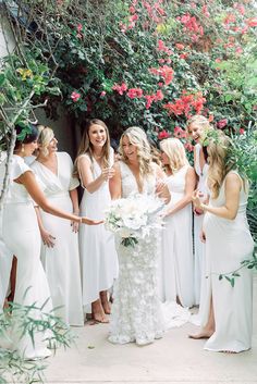 a group of women standing around each other in front of flowers and greenery on the ground