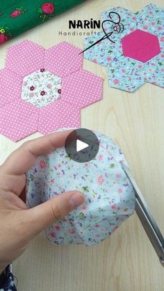 someone is cutting out some fabric to make hexagons with scissors on a table