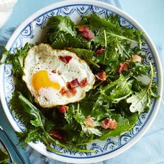 an egg and spinach salad on a blue and white plate with utensils