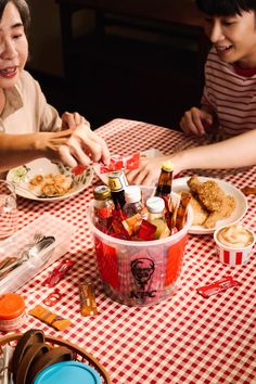 two people sitting at a table with food and drinks