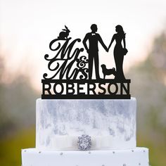 a wedding cake topper that says mr and mrs robertson on it with a bride and groom holding hands