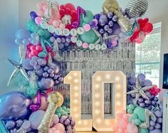 the balloon arch is decorated with balloons, streamers and lights for an 10th birthday celebration