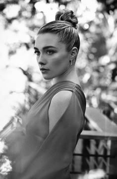 a black and white photo of a woman with her hair in a topknot