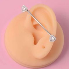 an ear piercing is shown on top of a pink surface, with two diamonds in the middle