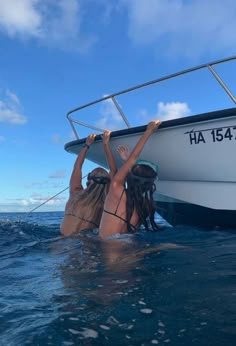 two people in the water on a boat with their hands up to the side,