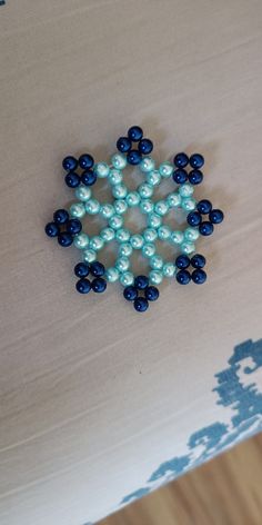 a blue and white beaded snowflake sitting on top of a bed