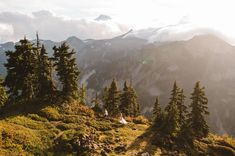 the sun shines through the clouds over mountains and trees