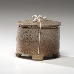 a brown and white ceramic container with rope on top