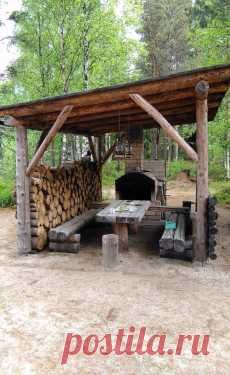 a wooden shelter with logs stacked under it