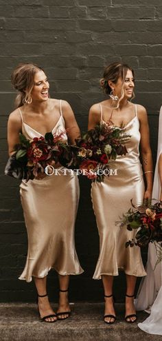 three bridesmaids in gold dresses standing next to each other and holding bouquets