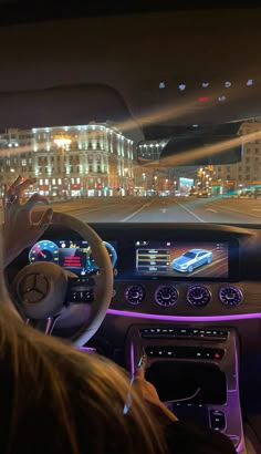 the interior of a car is lit up at night with city lights in the background