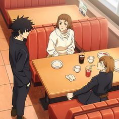 two people sitting at a table in a restaurant, one is talking to the other