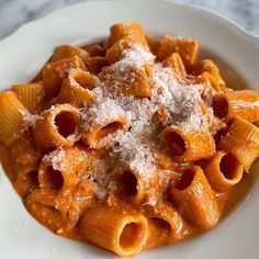 a white plate topped with pasta covered in sauce and parmesan cheese