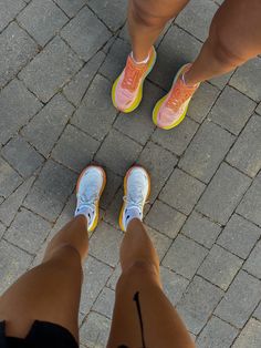 two people standing next to each other on a brick walkway with their feet crossed and one person wearing yellow shoes