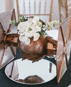 a vase with white flowers in it sitting on top of a table next to two mirrors