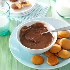 there is a bowl of chocolate and some cookies on the plate next to it with a spoon in it