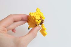 a hand holding a yellow lego toy that looks like a giraffe