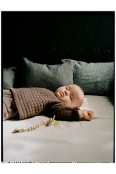 a baby laying on top of a bed next to pillows