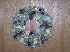 a crocheted wreath hanging on a wooden door with brown and blue trimmings