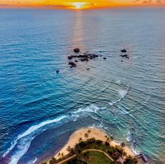 an aerial view of the beach and ocean at sunset