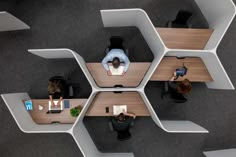 an overhead view of people working at desks in hexagonal cubicles on the floor