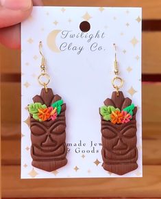 a pair of brown tiki earrings with colorful flowers on the front and back of them