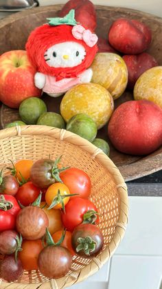 a basket filled with lots of different types of fruit next to a hello kitty stuffed animal