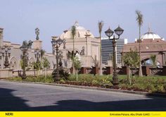 a large building with lots of lights on it's sides and palm trees in the foreground