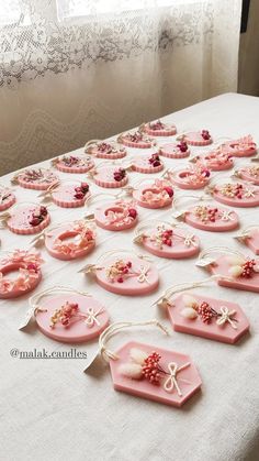 a table topped with lots of pink plates covered in buttons and beads on top of a white table cloth