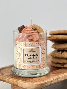 a glass jar filled with cookies sitting on top of a wooden table next to a stack of cookies