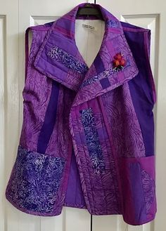 a purple jacket hanging on a door with a flower in the center and an embroidered design on it